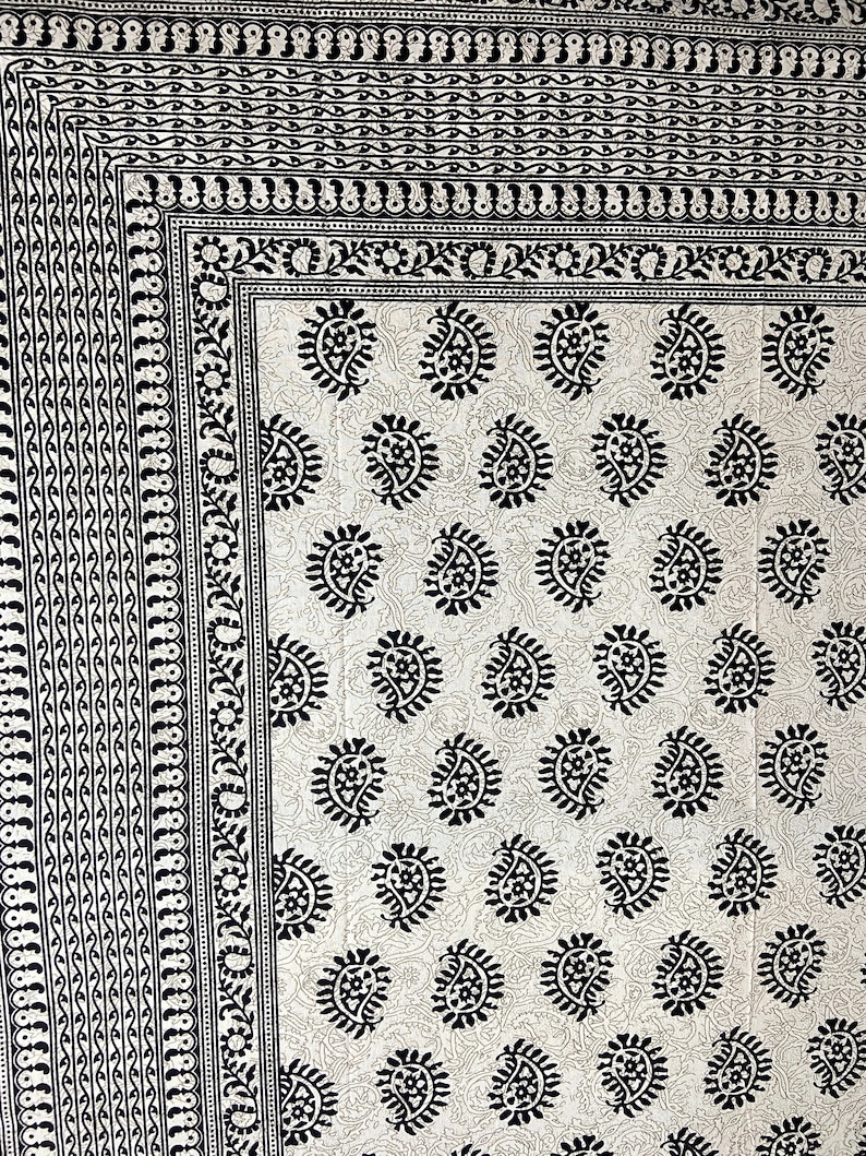 Peut inclure: Un tissu blanc avec un motif paisley noir. Le tissu a une bordure avec un motif r&eacute;p&eacute;titif noir et blanc.
