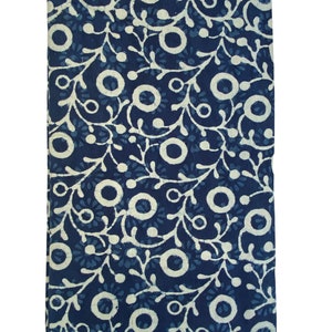 May include: A blue cotton fabric with a white floral pattern. The pattern features small white circles and swirls.