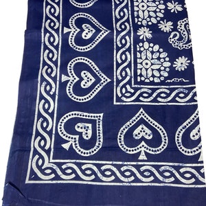 Puede incluir: Una tela azul con un patrón blanco de corazones, flores y un diseño de cadena. La tela está enrollada en la parte superior.