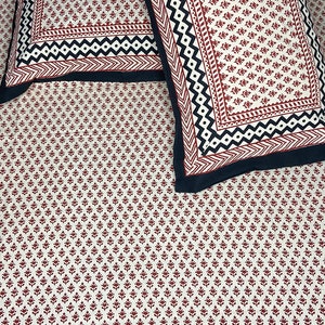 Puede incluir: Dos fundas de almohada blancas con un patr&oacute;n floral rojo y negro. Las fundas de almohada tienen un borde negro con un dise&ntilde;o geom&eacute;trico.