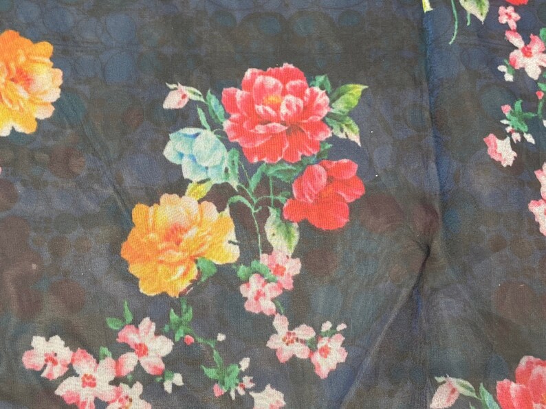 Puede incluir: Una tela azul oscuro con un estampado floral con flores rosas, rojas, amarillas y azules. Las flores est&aacute;n dispuestas en un patr&oacute;n aleatorio y est&aacute;n rodeadas de hojas verdes.