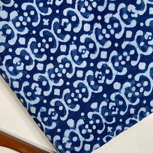 Peut inclure: Tissu bleu indigo avec un motif blanc de volutes et de points répétés. Le tissu a un aspect texturé, tissé à la main.