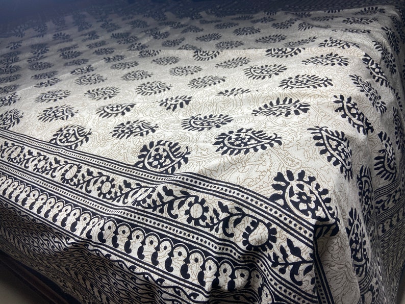 Peut inclure: Une couvre-lit en coton blanc avec un motif paisley noir. La couvre-lit a une bordure avec un motif floral.