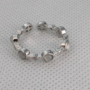 May include: A silver ring with a row of white stones set in a decorative design.