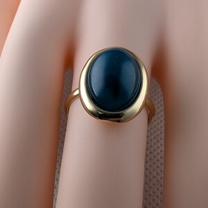 May include: A gold ring with a large oval-shaped dark blue gemstone.
