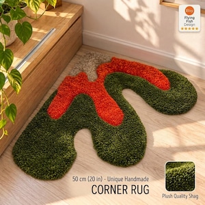 Op de afbeelding: Een onregelmatig gevormd hoekkleed met een pluche shag-textuur in donker olijfgroen, feloranje en lichtbeige. Het kleed is gelabeld als 50 cm (20 in) - Unique Handmade CORNER RUG en Plush Quality Shag, met een klein detail inzetstuk.