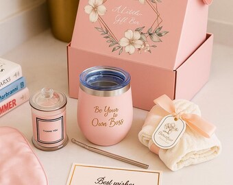 May include: A pink gift set with a box featuring floral designs and the text "A Little Gift Box." Includes a pink tumbler with "Be Your Own Boss," a candle, a sleep mask, a card, and a small towel.