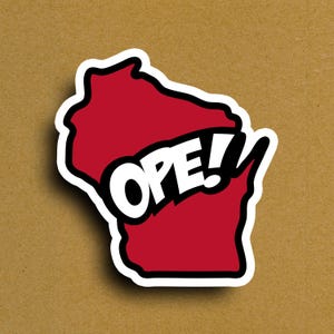 May include: A sticker featuring the outline of Wisconsin in red, with the word "OPE!" in white and black across the center. The sticker has a white border and is set against a brown background.