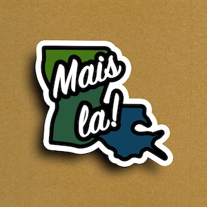 May include: A sticker featuring the outline of Louisiana in green and blue, with the words "Mais la!" in white script. The sticker has a white border and is set against a brown background.