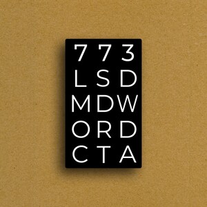 May include: A black rectangular sign with white text. The text includes the numbers "773" and the letters "LSD MDW ORD CTA". The sign is set against a tan background.