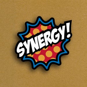 May include: A sticker with the word "SYNERGY!" in bold white letters. The sticker has a red background with yellow polka dots, a black outline, and a blue jagged border. The background is a light brown color.