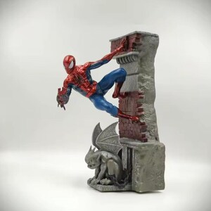 May include: A Spider-Man figurine in a dynamic pose, climbing a brick and stone structure. The figure is in a classic red and blue costume. A gargoyle statue is at the base of the structure. The overall design is detailed and captures the essence of the superhero.