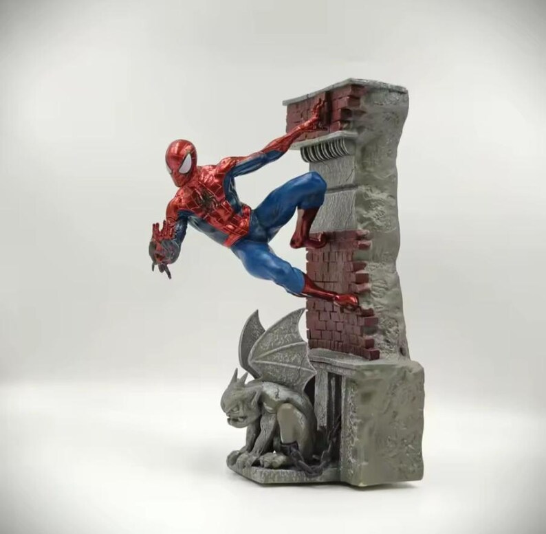 May include: A Spider-Man figurine in a dynamic pose, climbing a brick and stone structure. The figure is in a classic red and blue costume. A gargoyle statue is at the base of the structure. The overall design is detailed and captures the essence of the superhero.