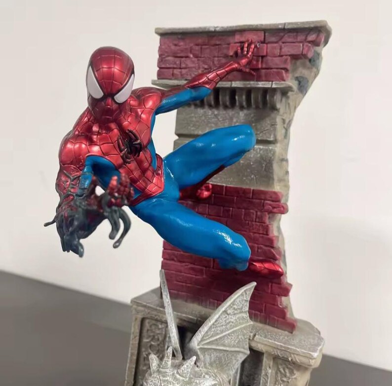 May include: A detailed figurine of Spider-Man in a dynamic pose, clad in a red and blue suit. The figure is set against a backdrop of a brick wall and a gargoyle-adorned structure, capturing a scene of action and adventure.