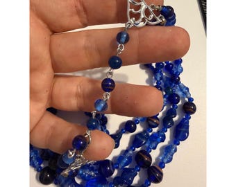 Collar llamativo de cuentas de vidrio de múltiples hebras azul vintage con cierre de palanca en tono plateado.