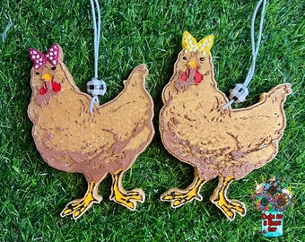 May include: Two brown wooden chicken ornaments with red and yellow bows. The chickens are hanging from white strings with black and white checkered beads.