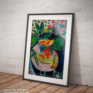 Puede incluir: Una impresión enmarcada de una pintura que representa un cuenco de peces dorados, rodeado de hojas verdes y flores rosas. El cuenco está sobre una mesa con un mantel azul. La pintura está en un marco negro.