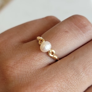 May include: A gold wire ring with a single white pearl. The ring is simple and elegant.