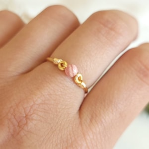 May include: A delicate gold ring with two small pink gemstone beads.