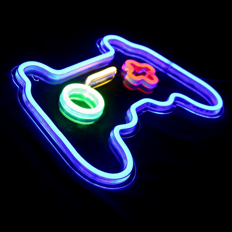 May include: A neon blue, green, and red gamepad sign. The sign is shaped like a video game controller with a circle button and a plus sign.