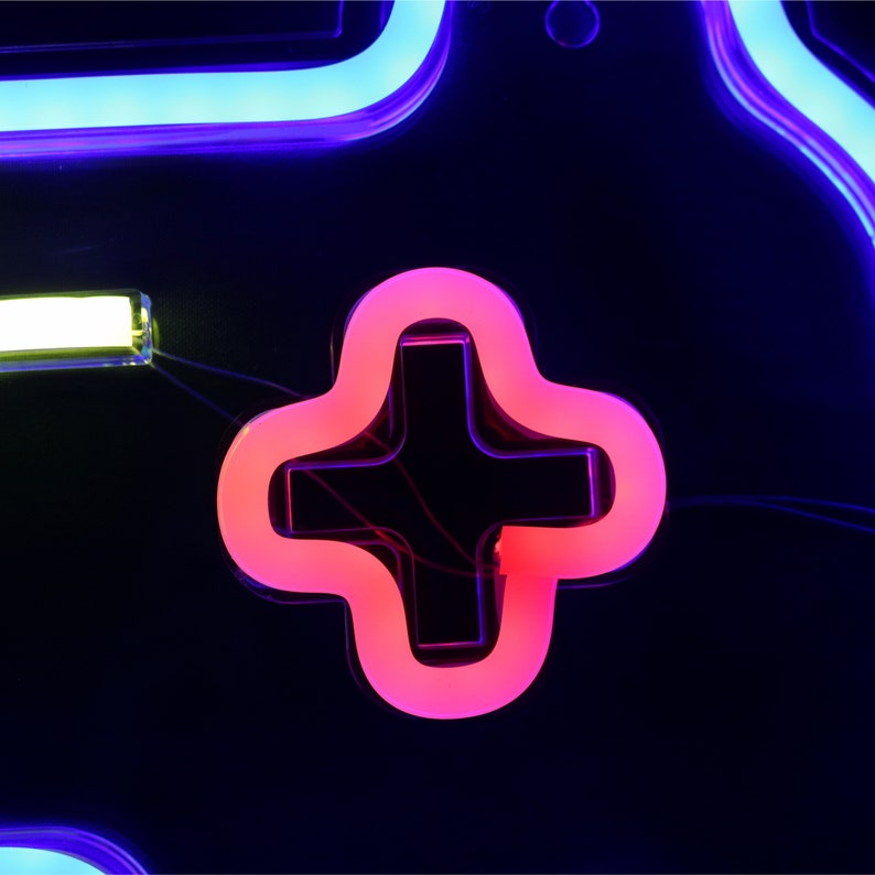 May include: A neon sign shaped like a video game controller with a pink plus button. The sign is lit up in blue and white.