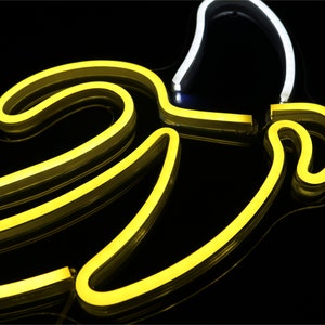 May include: A neon sign shaped like a banana with a yellow outline and a white interior.