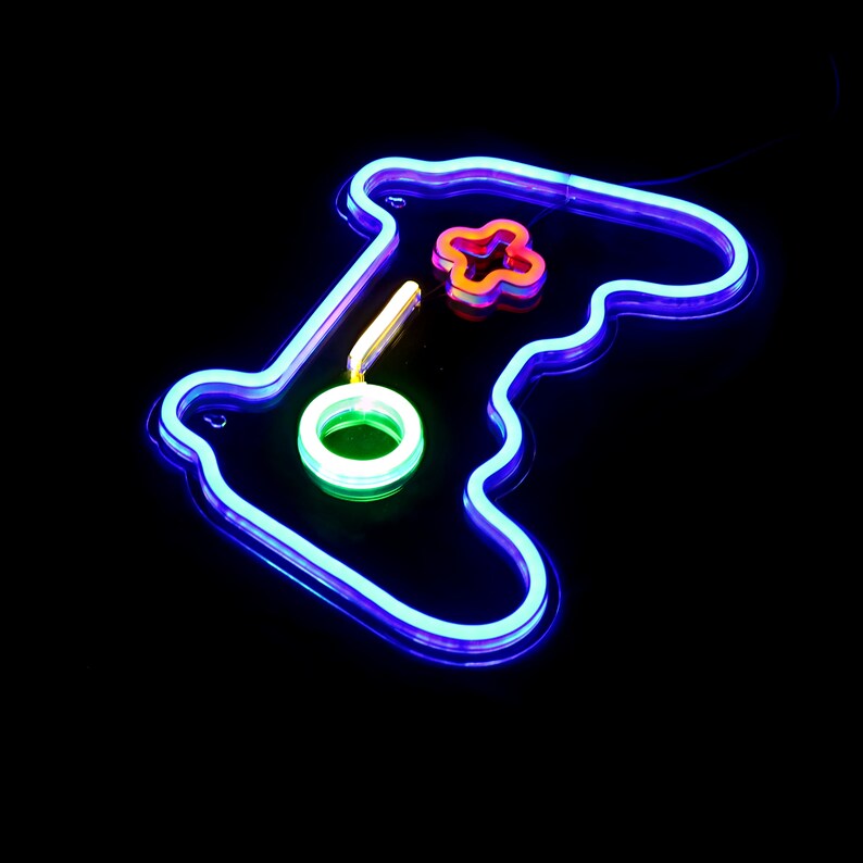 May include: A blue neon sign shaped like a video game controller. The sign has a green circle, a red cross, and a yellow button.
