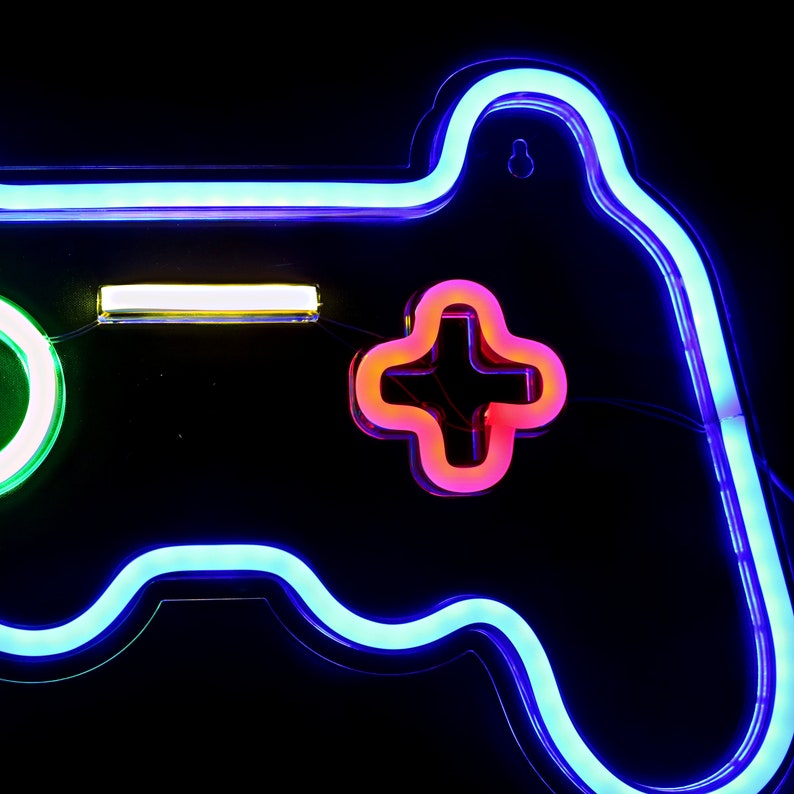 May include: A neon blue and green video game controller sign with a red plus button. The sign is lit up and has a white light bar on the top.