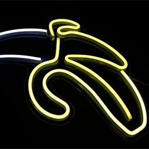 May include: A neon sign shaped like a banana, with a yellow glow against a black background.