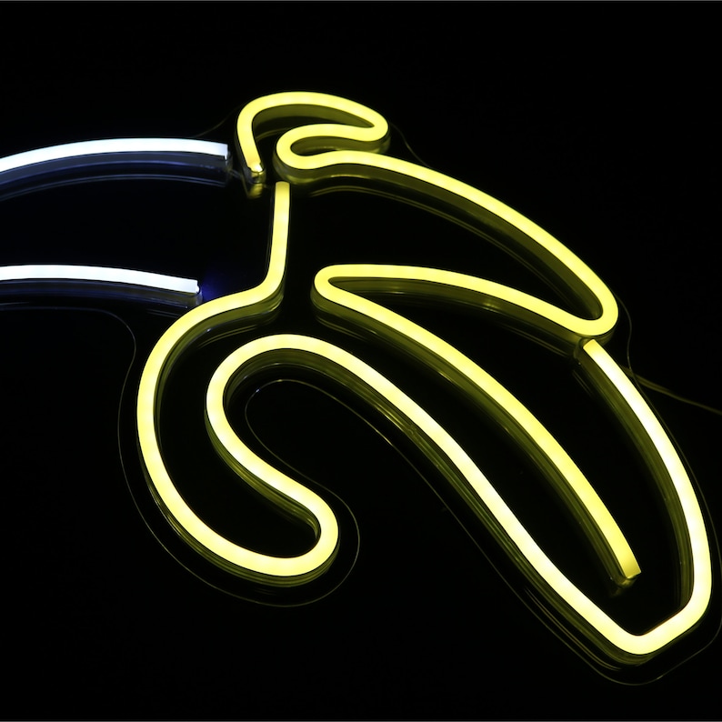 May include: A neon sign shaped like a banana, with a yellow glow against a black background.
