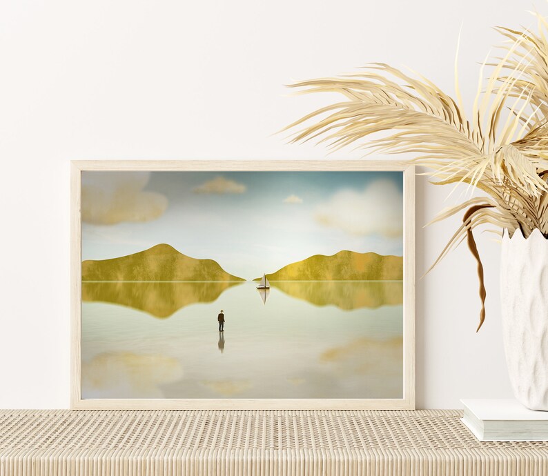Puede incluir: Una impresi&oacute;n enmarcada de una pintura de paisaje minimalista con un solo velero en un cuerpo de agua tranquilo. La pintura presenta dos colinas verdes reflejadas en el agua, y una figura solitaria de pie en la orilla.