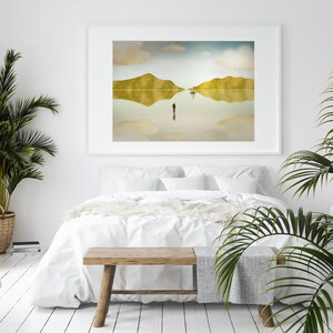 Puede incluir: Una cama blanca con ropa de cama blanca y un banco de madera delante. Una impresi&oacute;n enmarcada de un paisaje con un barco y una persona de pie en el agua cuelga de la pared detr&aacute;s de la cama. Una planta en maceta est&aacute; en el lado izquierdo de la imagen.