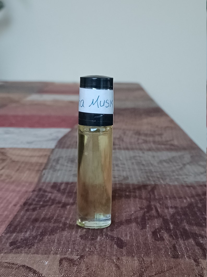 Może przedstawiać: Przezroczysta szklana butelka z rolką z czarną zakrętką i białą etykietą z napisem "Ina Musk".