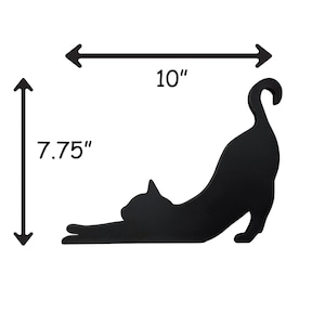 Black wood cat silhouette wall decor. The cat is stretched out with its tail curled up. The silhouette is 10 inches wide and 7.75 inches tall.