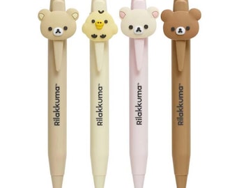 Può includere: Set di quattro penne con fusti di colori diversi e personaggi Rilakkuma. I personaggi includono un orso marrone, un pulcino giallo, un orso rosa e un orso marrone. Ogni penna ha la scritta "Rilakkuma" stampata sul fusto.