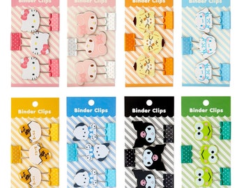 Könnte beinhalten: Ein Set mit zehn Binderclips mit verschiedenen Comicfiguren. Jeder Clip ist einzeln verpackt mit einem gestreiften Hintergrund und dem Text "Binder Clips". Die Figuren sind Hello Kitty, My Melody, Pompompurin, Keroppi und Kuromi.