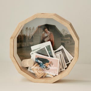 May include: A wooden octagonal box with a glass front, filled with photos and a cork. The box has the text "Jennifer & Jordan My Best Memories Are With You" printed on the front.