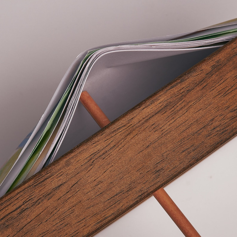 Puede incluir: Primer plano de un marco de madera con una pila de papeles en su interior. Los papeles est&aacute;n doblados por la mitad y tienen un patr&oacute;n verde y blanco.