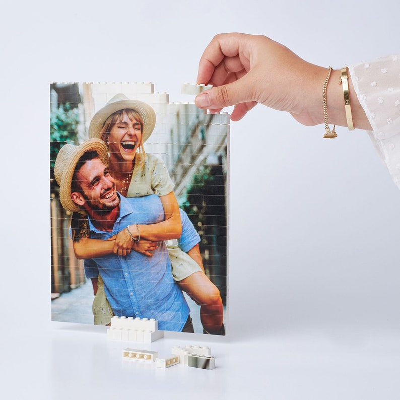 May include: A couple is pictured in a photo puzzle. The man is wearing a blue shirt and the woman is wearing a white shirt. They are both smiling and appear to be having fun.