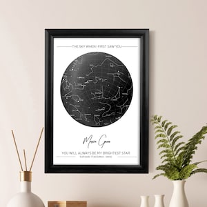 Può includere: Una stampa incorniciata di una mappa stellare in bianco e nero. La stampa presenta un grafico stellare circolare con costellazioni e il testo "THE SKY WHEN I FIRST SAW YOU". Sotto la mappa stellare c'è il nome "Maria Green" e il testo "YOU WILL ALWAYS BE MY BRIGHTEST STAR".