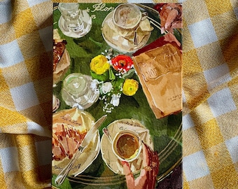 Op de afbeelding: Een aquarel schilderij van een cafétafel met twee kopjes koffie, een bord met gebak, een boek en een boeket bloemen. De tafel is bedekt met een groen tafelkleed en de achtergrond is een wazig beeld van een café.