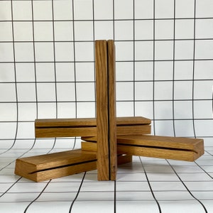 May include: Four wooden shelves stacked on top of each other, creating a unique geometric design. The shelves are made of natural wood with a light brown color and a smooth finish.
