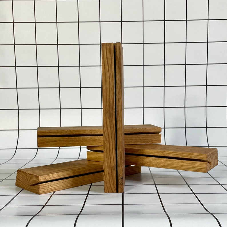 May include: Four wooden shelves stacked on top of each other, creating a unique geometric design. The shelves are made of natural wood with a light brown color and a smooth finish.