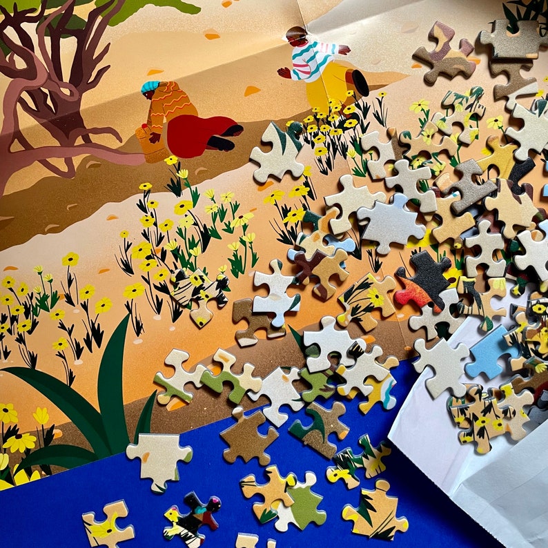 Puede incluir: Un rompecabezas completado con una ilustraci&oacute;n colorida de un &aacute;rbol, flores y personas. Las piezas del rompecabezas est&aacute;n esparcidas alrededor de un sobre blanco y una superficie azul.