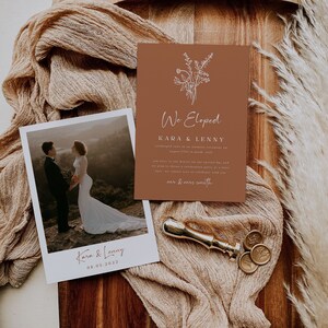 Op de afbeelding: Een huwelijksaankondiging met een bruine achtergrond en witte tekst. De kaart zegt "We Eloped" en bevat de namen "Kara & Lenny". De kaart bevat ook een kleine illustratie van een boeket bloemen. Een foto van het paar is opgenomen in een wit kader met de tekst "Kara & Lenny 08.05.2022".