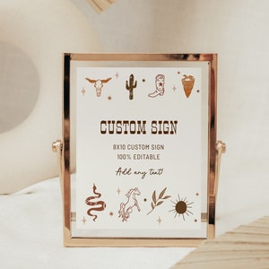 May include: A gold-framed sign with a white background and brown illustrations of a cactus, cowboy boot, skull, and other western-themed imagery. The sign reads "CUSTOM SIGN 8x10 CUSTOM SIGN 100% EDITABLE Add any text".