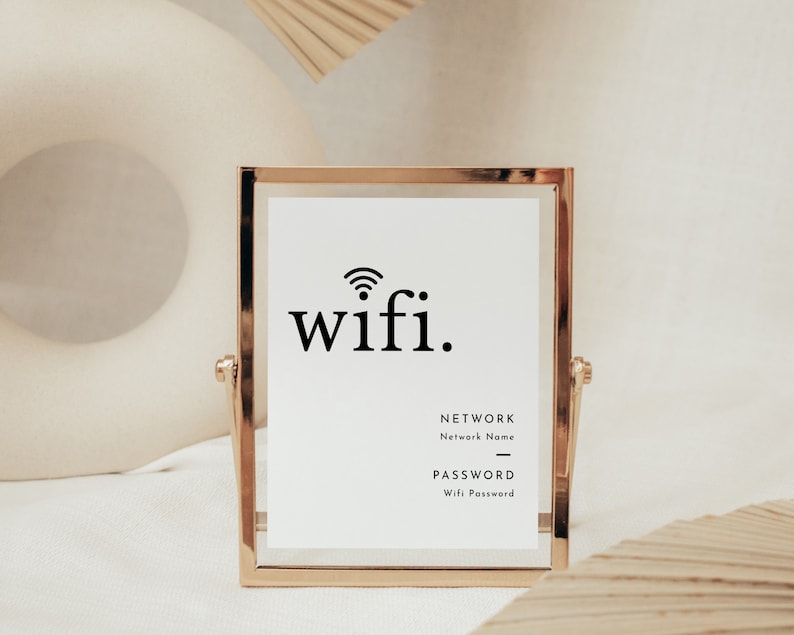 May include: A gold-framed sign with the word "wifi" in black, along with a wifi symbol. Below, the sign includes fields for network name and password. The sign is displayed on a white background.