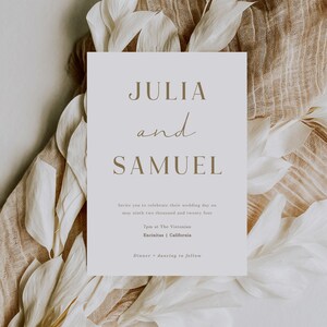 Pu&ograve; includere: Un invito di nozze con un design semplice che presenta i nomi Julia e Samuel in un carattere marrone. L'invito riporta la data, l'ora, il luogo e le informazioni sul ricevimento del matrimonio.