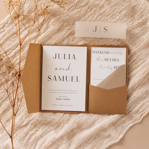 Pu&ograve; includere: Una cartella tascabile di carta marrone con un cartoncino bianco all'interno. Il cartoncino riporta il testo "Julia e Samuel" in un carattere moderno. La cartella contiene un cartoncino bianco pi&ugrave; piccolo all'interno con il testo "Weekend events the details kindly RSVP".