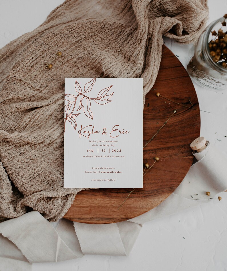 May include: A minimalist wedding invitation with a brown line drawing of a leafy branch. The text reads "Kayla & Eric" and includes the date "JAN 12 2023" and the location "byron tides estate byron bay | new south wales".